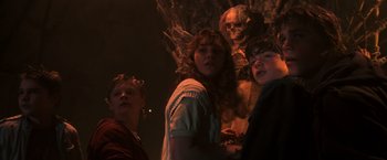 Movie still from “The Goonies” (1985), directed by Richard Donner – A group of people standing next to a skeleton; Medium shot, Low angle
