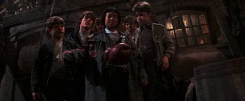 Movie still from “The Goonies” (1985), directed by Richard Donner – A group of young men standing next to each other in a room; Medium shot, Low angle