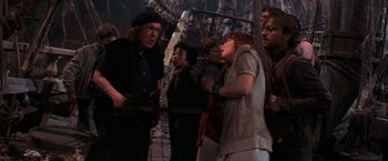 Movie still from “The Goonies” (1985), directed by Richard Donner – A group of people standing next to each other in a room; Medium shot, Over the shoulder angle