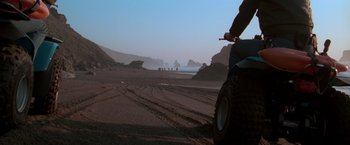 Movie still from “The Goonies” (1985), directed by Richard Donner – A person riding a motorcycle on top of a dirt road; Wide shot, Low angle