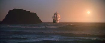 Movie still from “The Goonies” (1985), directed by Richard Donner – A large sail boat in the ocean at sunset; Extreme Wide shot, Low angle