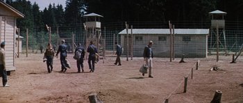 Movie still from “The Great Escape” (1963), directed by John Sturges – A group of people walking in a fenced in area; Extreme Wide shot, High angle