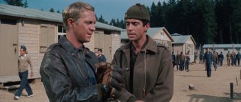 Movie still from “The Great Escape” (1963), directed by John Sturges – Two men are standing outside talking to each other; Medium shot, Over the shoulder angle