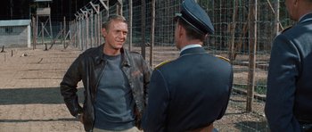 Movie still from “The Great Escape” (1963), directed by John Sturges – A man in a leather jacket talking to a man in a uniform; Medium shot, Over the shoulder angle