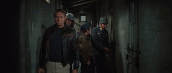Movie still from “The Great Escape” (1963), directed by John Sturges – A group of men in uniform walking down a hall way; Medium shot, Over the shoulder angle