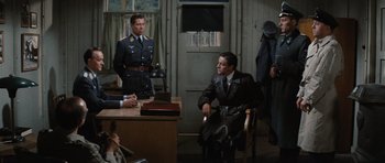 Movie still from “The Great Escape” (1963), directed by John Sturges – A group of men sitting at a table in front of a door; Wide shot, High angle
