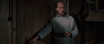 Movie still from “The Great Escape” (1963), directed by John Sturges – A man wearing a sweater is holding something in his hand; Medium shot, Low angle