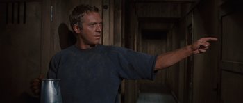 Movie still from “The Great Escape” (1963), directed by John Sturges – A man in a blue shirt is pointing to something; Medium shot, Low angle
