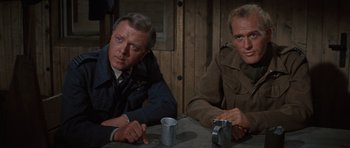 Movie still from “The Great Escape” (1963), directed by John Sturges – A couple of men sitting at a wooden table; Medium shot, Low angle