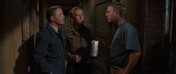 Movie still from “The Great Escape” (1963), directed by John Sturges – A group of men standing next to each other in a room; Medium shot, Over the shoulder angle