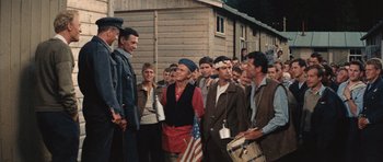 Movie still from “The Great Escape” (1963), directed by John Sturges – A group of men standing next to each other in front of a building; Wide shot, High angle