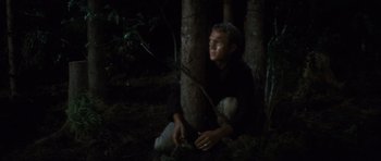 Movie still from “The Great Escape” (1963), directed by John Sturges – A man sitting next to a tree in the dark; Medium shot, High angle