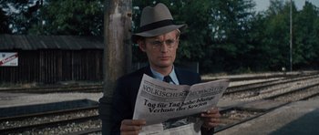 Movie still from “The Great Escape” (1963), directed by John Sturges – A man wearing a hat and glasses reading a newspaper; Close Up shot, Over the shoulder angle