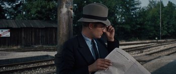 Movie still from “The Great Escape” (1963), directed by John Sturges – A man in a hat and glasses reading a newspaper; Close Up shot, Over the shoulder angle