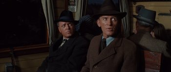 Movie still from “The Great Escape” (1963), directed by John Sturges – A couple of men sitting next to each other on top of a bus; Medium shot, Over the shoulder angle