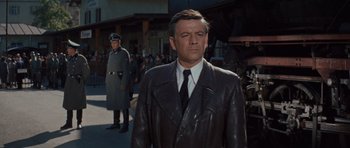 Movie still from “The Great Escape” (1963), directed by John Sturges – A man wearing a leather jacket and a tie in front of a crowd; Medium shot, Low angle