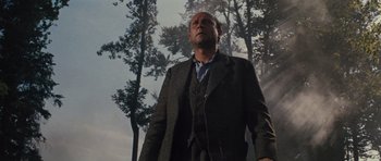 Movie still from “The Great Escape” (1963), directed by John Sturges – A man standing in front of a forest with trees in the background; Medium shot, Low angle