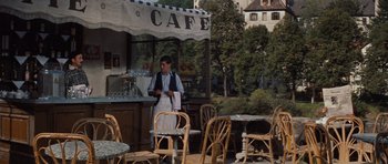 Movie still from “The Great Escape” (1963), directed by John Sturges – A man standing in front of an outdoor cafe; Wide shot, High angle
