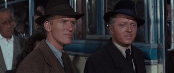 Movie still from “The Great Escape” (1963), directed by John Sturges – Two men in suits and hats standing next to each other in front of a window; Close Up shot, Low angle