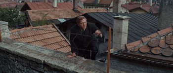 Movie still from “The Great Escape” (1963), directed by John Sturges – A man in a black suit is on the roof; Wide shot, High angle