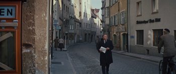 Movie still from “The Great Escape” (1963), directed by John Sturges – A man walking down a street holding a newspaper; Wide shot, High angle