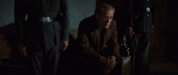 Movie still from “The Great Escape” (1963), directed by John Sturges – A man sitting on a couch in a dark room; Medium shot, Low angle