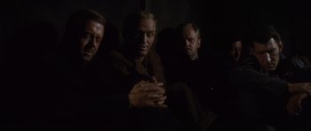 Movie still from “The Great Escape” (1963), directed by John Sturges – A group of men sitting next to each other in the dark; Medium shot, High angle