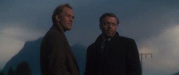Movie still from “The Great Escape” (1963), directed by John Sturges – Two men standing next to each other on a cloudy day; Medium shot, Low angle