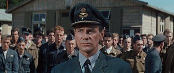 Movie still from “The Great Escape” (1963), directed by John Sturges – A group of men in uniform standing next to each other in front of a building; Close Up shot, Low angle