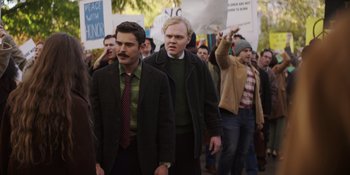 Movie still from “The Greatest Beer Run Ever” (2022), directed by Peter Farrelly – A group of people marching down a street holding signs; Medium shot, Over the shoulder angle