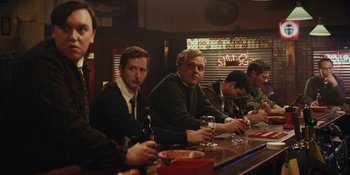 Movie still from “The Greatest Beer Run Ever” (2022), directed by Peter Farrelly – A group of men sitting at a bar drinking; Medium shot, Over the shoulder angle