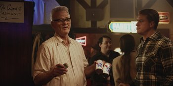 Movie still from “The Greatest Beer Run Ever” (2022), directed by Peter Farrelly – An older man standing in front of a group of people; Medium shot, Over the shoulder angle