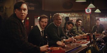 Movie still from “The Greatest Beer Run Ever” (2022), directed by Peter Farrelly – A group of men sitting at a bar drinking beer; Medium shot, Over the shoulder angle