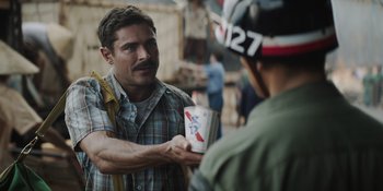 Movie still from “The Greatest Beer Run Ever” (2022), directed by Peter Farrelly – A man handing a cup to another man on the side of the street; Close Up shot, Over the shoulder angle