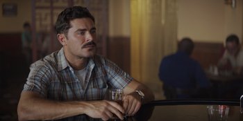 Movie still from “The Greatest Beer Run Ever” (2022), directed by Peter Farrelly – A man sitting at a table holding a glass of beer; Close Up shot, Over the shoulder angle