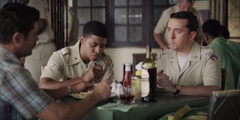 Movie still from “The Greatest Beer Run Ever” (2022), directed by Peter Farrelly – A group of men sitting at a table eating food; Medium shot, Over the shoulder angle