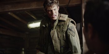Movie still from “The Greatest Beer Run Ever” (2022), directed by Peter Farrelly – A man in a military uniform standing next to a building; Medium shot, Over the shoulder angle