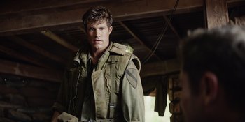 Movie still from “The Greatest Beer Run Ever” (2022), directed by Peter Farrelly – A young man in a military uniform is standing in a room; Medium shot, Over the shoulder angle