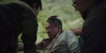 Movie still from “The Greatest Beer Run Ever” (2022), directed by Peter Farrelly – A man with a head injury being attended to by two other men; Medium shot, Low angle