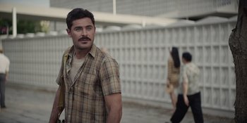 Movie still from “The Greatest Beer Run Ever” (2022), directed by Peter Farrelly – A man standing in front of a wall with people; Medium shot, Over the shoulder angle