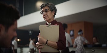 Movie still from “The Greatest Beer Run Ever” (2022), directed by Peter Farrelly – An older woman holding a clipboard while standing in a room; Close Up shot, Over the shoulder angle
