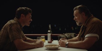 Movie still from “The Greatest Beer Run Ever” (2022), directed by Peter Farrelly – Two men sitting at a table with a bottle of wine and a bowl of pasta; Medium shot, Over the shoulder angle