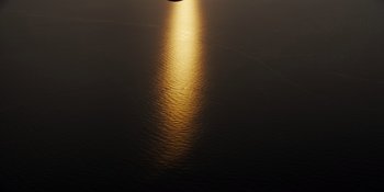 Movie still from “The Greatest Beer Run Ever” (2022), directed by Peter Farrelly – The sun is setting over the ocean with a boat in the background; Extreme Wide shot, High angle