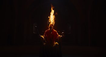 Movie still from “The Green Knight” (2021), directed by David Lowery – A man in a robe is holding a burning object in front of him; Extreme Wide shot, Low angle
