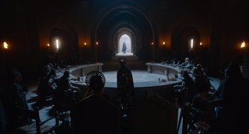 Movie still from “The Green Knight” (2021), directed by David Lowery – A group of people sitting in a large room; Extreme Wide shot, Over the shoulder angle