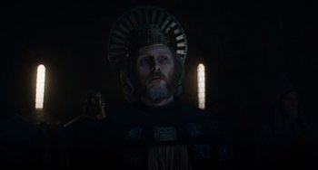 Movie still from “The Green Knight” (2021), directed by David Lowery – A man with a beard wearing a crown; Close Up shot, Low angle
