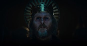 Movie still from “The Green Knight” (2021), directed by David Lowery – A man with a beard wearing a crown; Close Up shot, Low angle