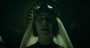 Movie still from “The Green Knight” (2021), directed by David Lowery – A woman wearing a crown and a black shirt; Close Up shot, Low angle