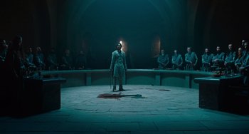Movie still from “The Green Knight” (2021), directed by David Lowery – A man standing on a stage with a sword; Wide shot, High angle