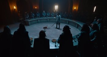 Movie still from “The Green Knight” (2021), directed by David Lowery – A group of people sitting around a round table; Wide shot, High angle